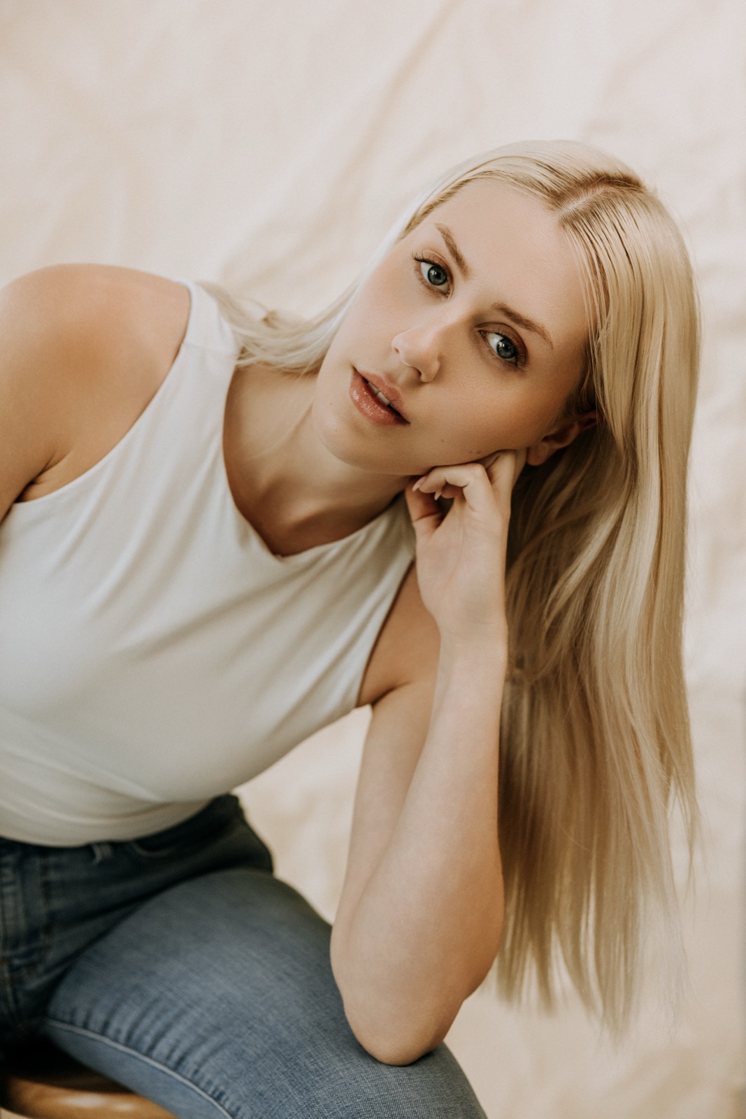 Ida Angelma in a white tank and jeans, chin on hand