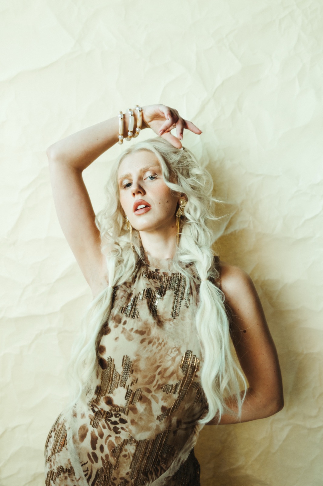 Ida Angelma in a leopard top, arm raised, on cream paper