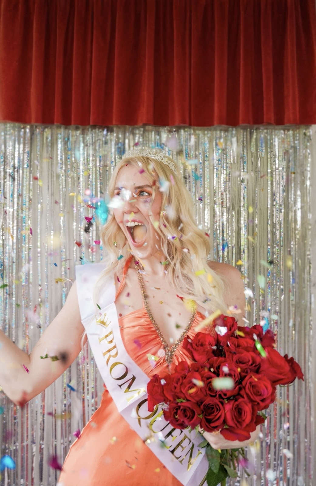 Ida Angelma as prom queen in an orange satin dress, throwing confetti