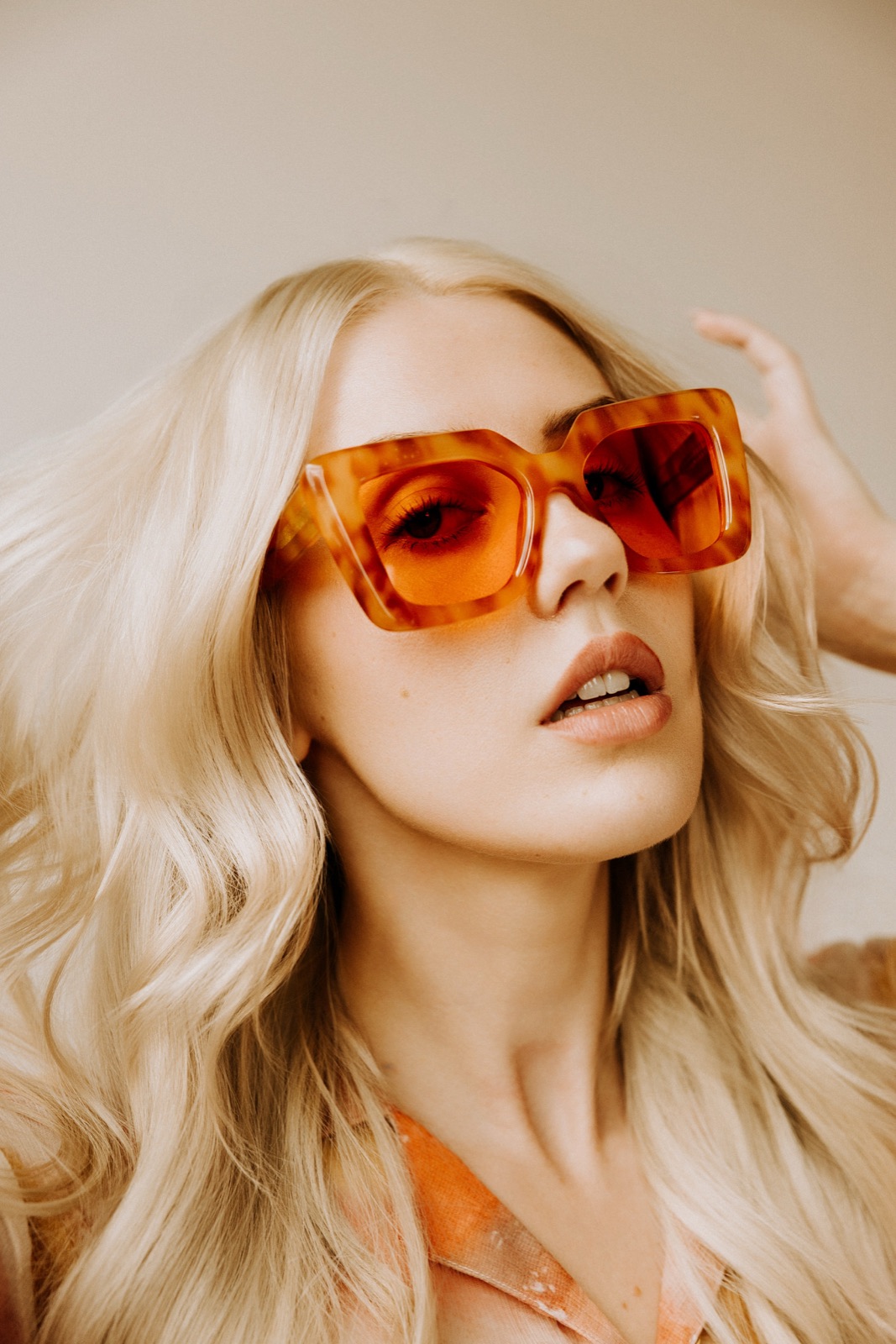 Ida Angelma in oversized orange sunglasses, close-up, hand in her hair