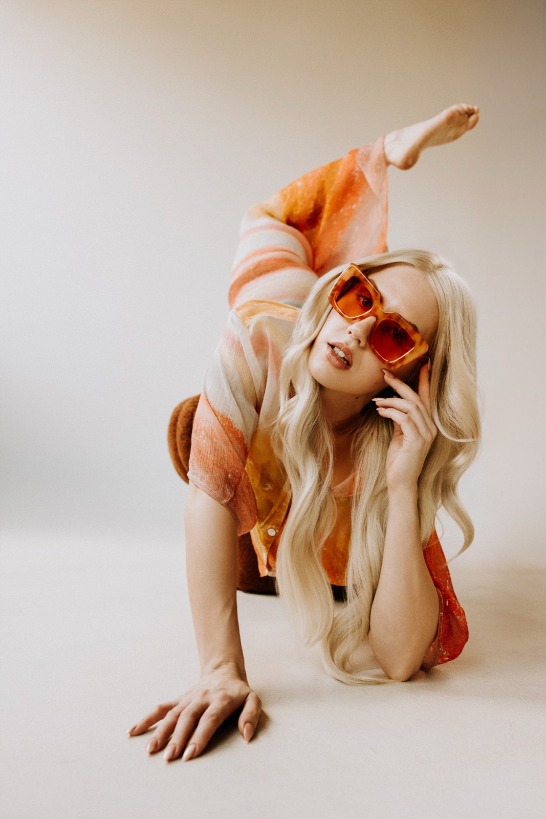 Ida Angelma in orange sunglasses, leg raised, on the floor