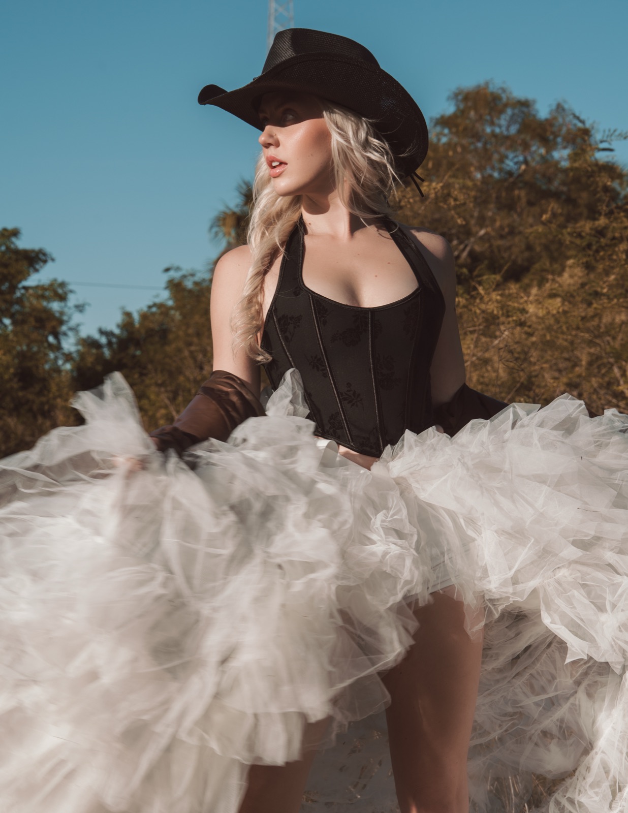 Ida Angelma in a black corset, cowboy hat and white tulle skirt