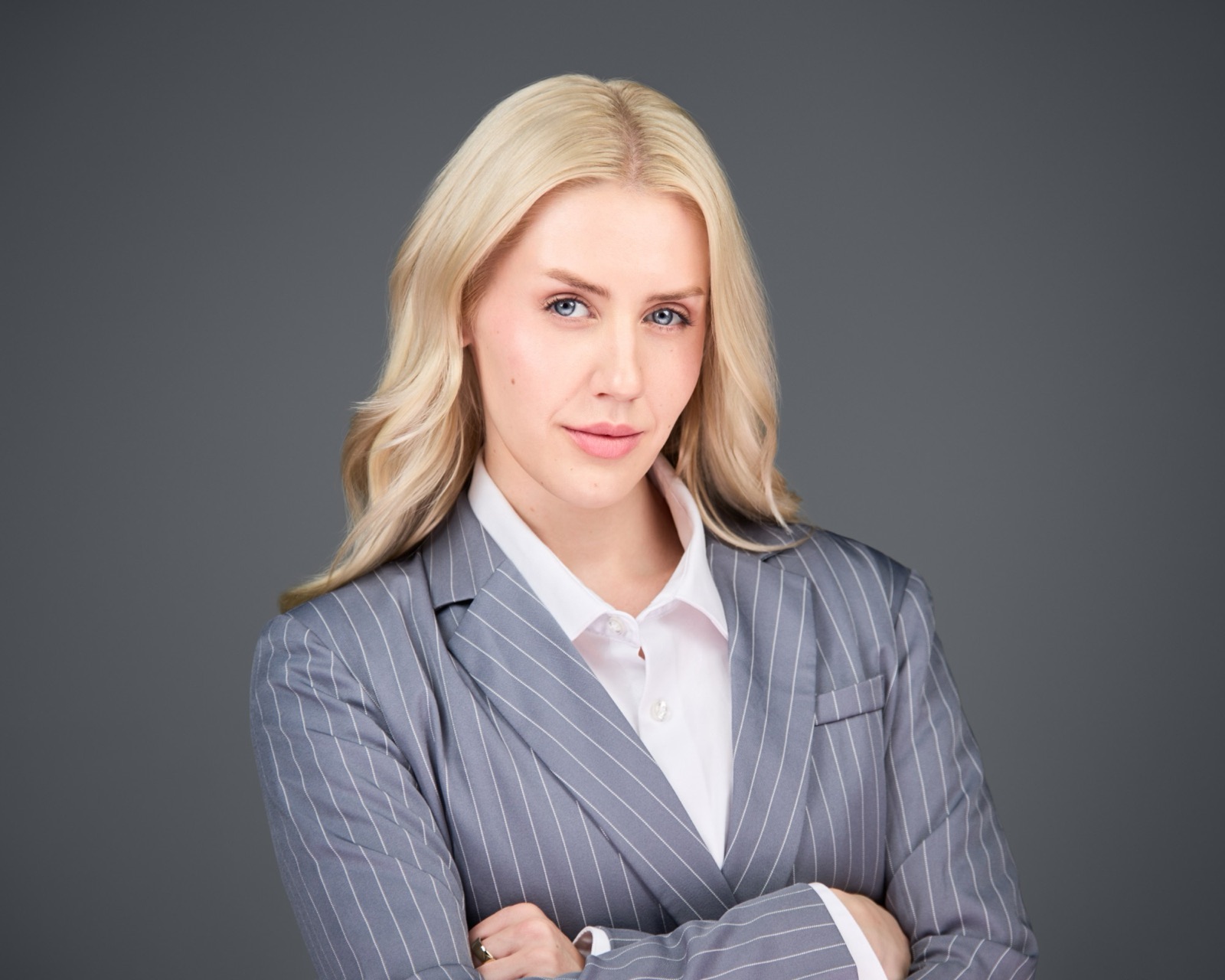 Ida Angelma in a pinstripe suit, arms crossed