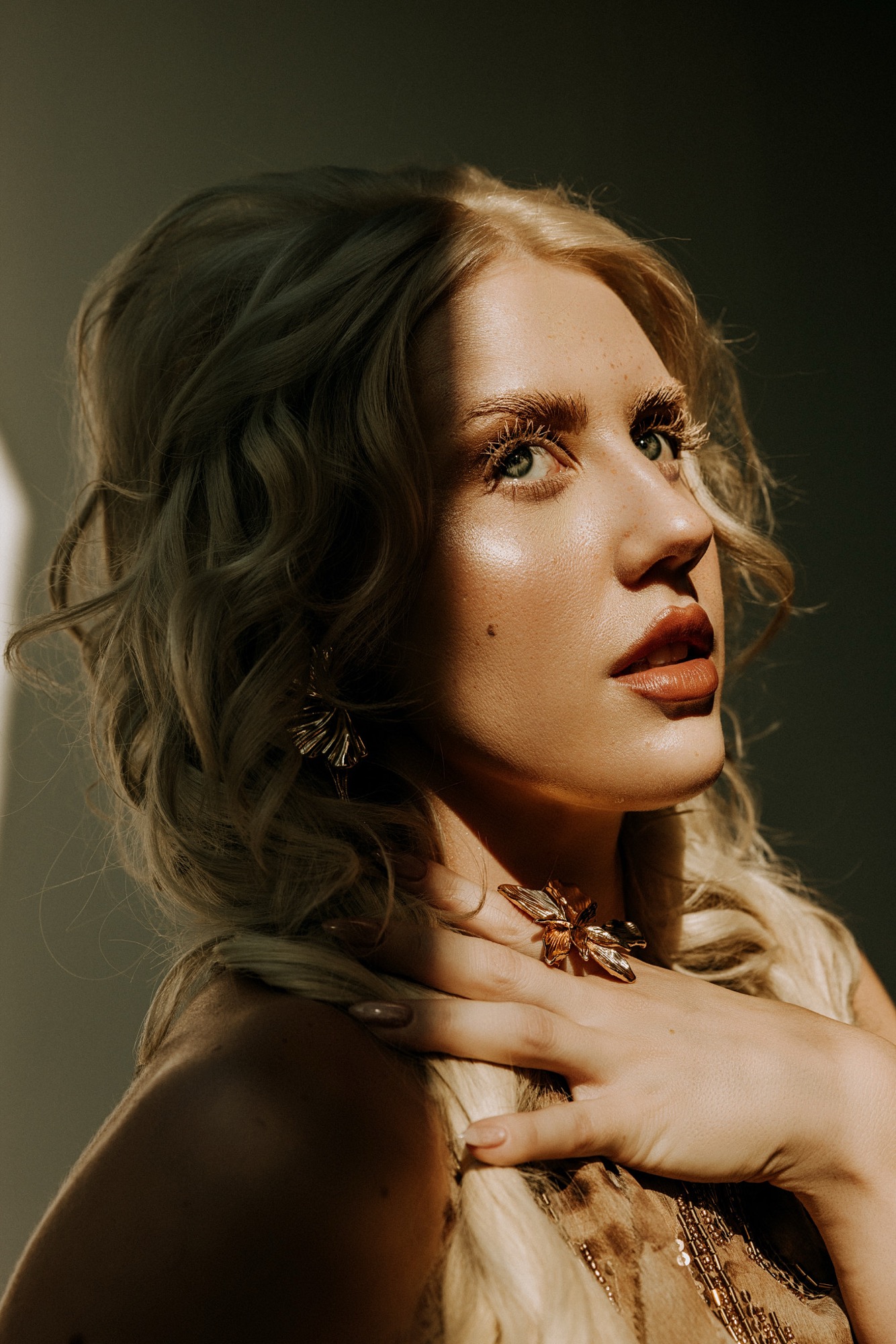 Ida Angelma in warm low light, hand at her collarbone